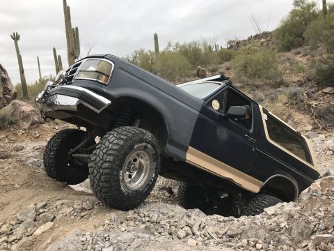 1991 Ford Bronco - This lifted Ford Bronco is shown off-roading in a desert environment with saguaro cacti.