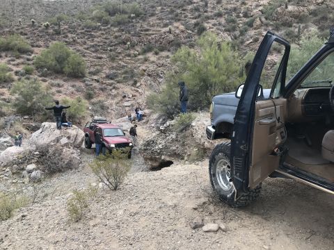 1991 Ford Bronco - Off-roading scene with a 1991 Ford Bronco and another SUV navigating a rocky desert trail.