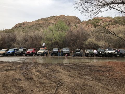 1991 Ford Bronco - A convoy of off-road vehicles stops in a shallow riverbed during an outing.