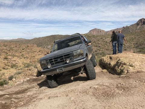 1991 Ford Bronco - This 1991 Ford Bronco is navigating a challenging off-road trail in a desert landscape.
