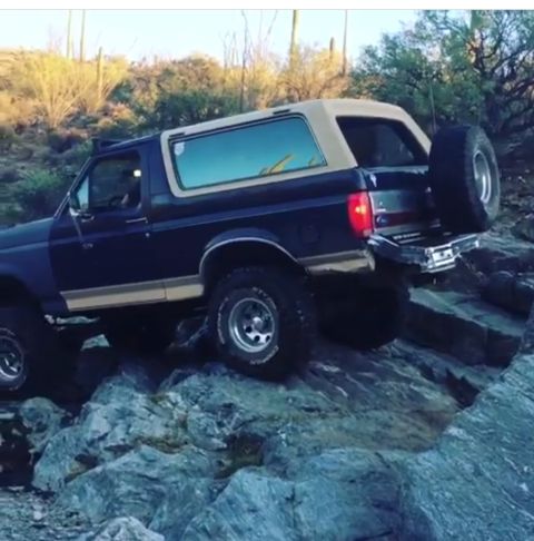 1991 Ford Bronco - A 1991 Ford Bronco navigates a rocky trail in a desert environment.