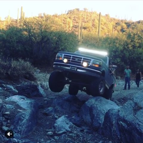 1991 Ford Bronco - A black Ford Bronco navigates a rocky trail, its front tires off the ground.