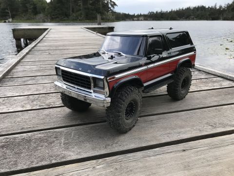 1989 Ford Bronco - A black and red Ford Bronco model sits on a wooden dock next to a lake.