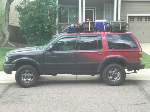 2000 Ford Explorer - Side view of a 2000 Ford Explorer SUV equipped with a roof rack carrying camping equipment.