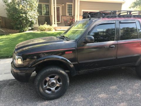 2000 Ford Explorer - This 2000 Ford Explorer is seen from a 3/4 front angle, a roof rack and red accents.