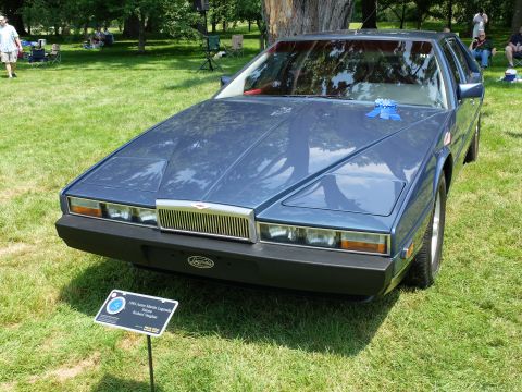 1971 Ford Ranchero - A blue Aston Martin Lagonda is displayed on a grassy field with people in the background.