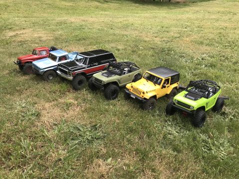 1989 Ford Bronco - A collection of remote-controlled off-road vehicles are lined up on a grassy field.