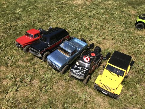 1989 Ford Bronco - A collection of RC vehicles are parked on a grassy lawn on a sunny day.