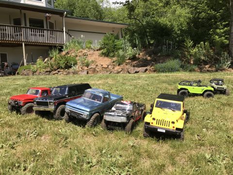 1989 Ford Bronco - A collection of RC vehicles, including trucks and jeeps, are displayed outdoors on a sunny day.