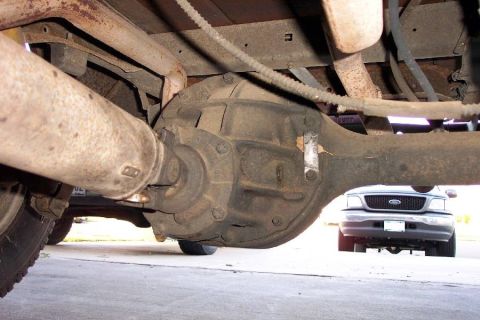 1968 Ford F-100 - Underside view of a solid rear axle housing with its cast pumpkin-style differential center section, drum brake backing plate at left, and…