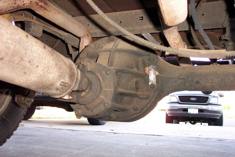 Underside view of rear axle differential housing, leaf spring and rusty exhaust on a pickup