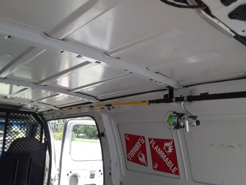 1999 Ford E250 - The interior of a van shows a fishing rod holder and two flammable material warning stickers.