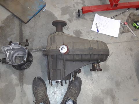 1996 Ford F-350 - A transfer case and its housing sit on a concrete floor, with a notebook and pen in the background.