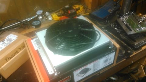 1992 Ford Bronco - An electric cooling fan sits on a workbench next to shipping boxes and various gauges.