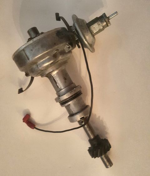 1973 Ford Mustang - A metal automotive distributor with a black gear and red wire connector is shown against a plain background.