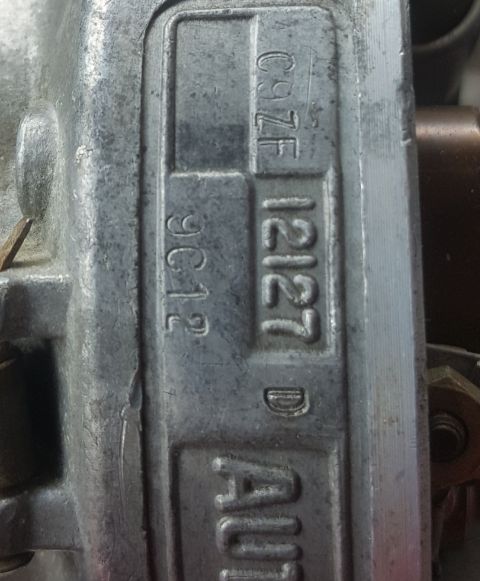 1973 Ford Mustang - A metal carburetor part displays stamped identification numbers, including C9ZF 12127 D and 9C12.