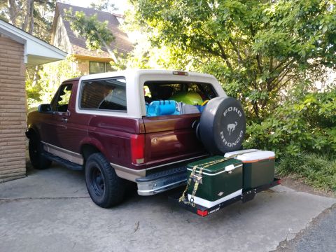 1996 Ford Bronco - 1996 Ford Bronco with camper shell loaded with items, parked outdoors.