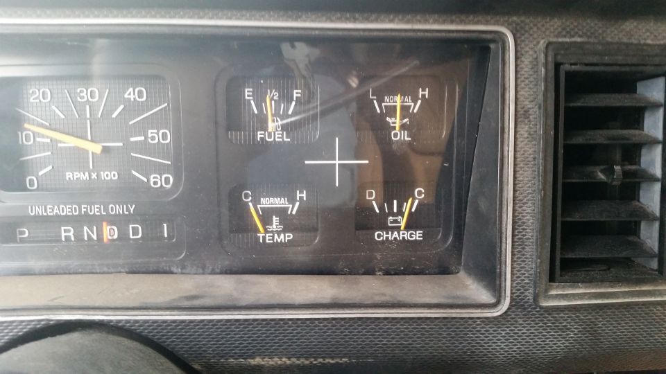 Dashboard gauges showing RPM, fuel, oil, temperature, and charge levels. Transmission selector is in Drive