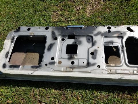 1976 Ford Ranchero - The interior of a car door, showing its internal structure and mounting points, lies on a grassy surface.