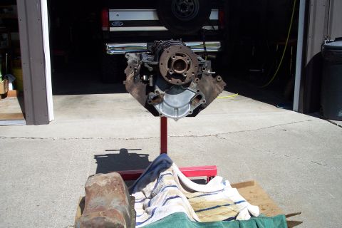 1995 Ford Bronco - Engine block on a stand in front of a garage with a Ford truck partially visible.