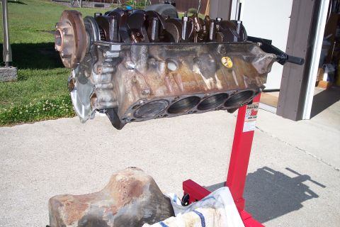 1995 Ford Bronco - Engine block and oil pan displayed on a stand outdoors.