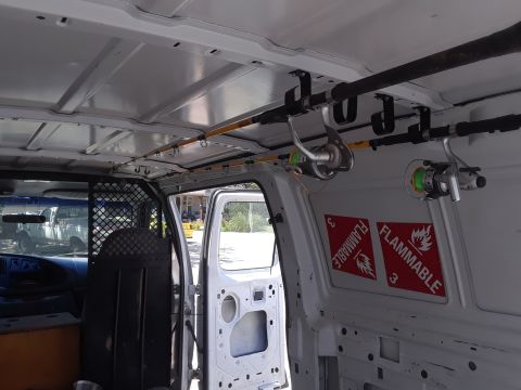 1999 Ford E250 - The cargo area of a van is equipped with fishing rod holders and safety hazard labels.