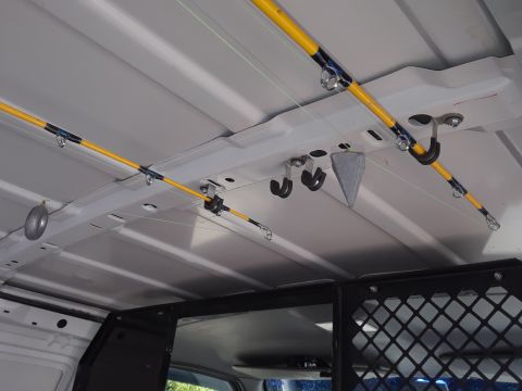 1999 Ford E250 - Fishing rods are neatly stored on ceiling racks within the cargo area of a van.