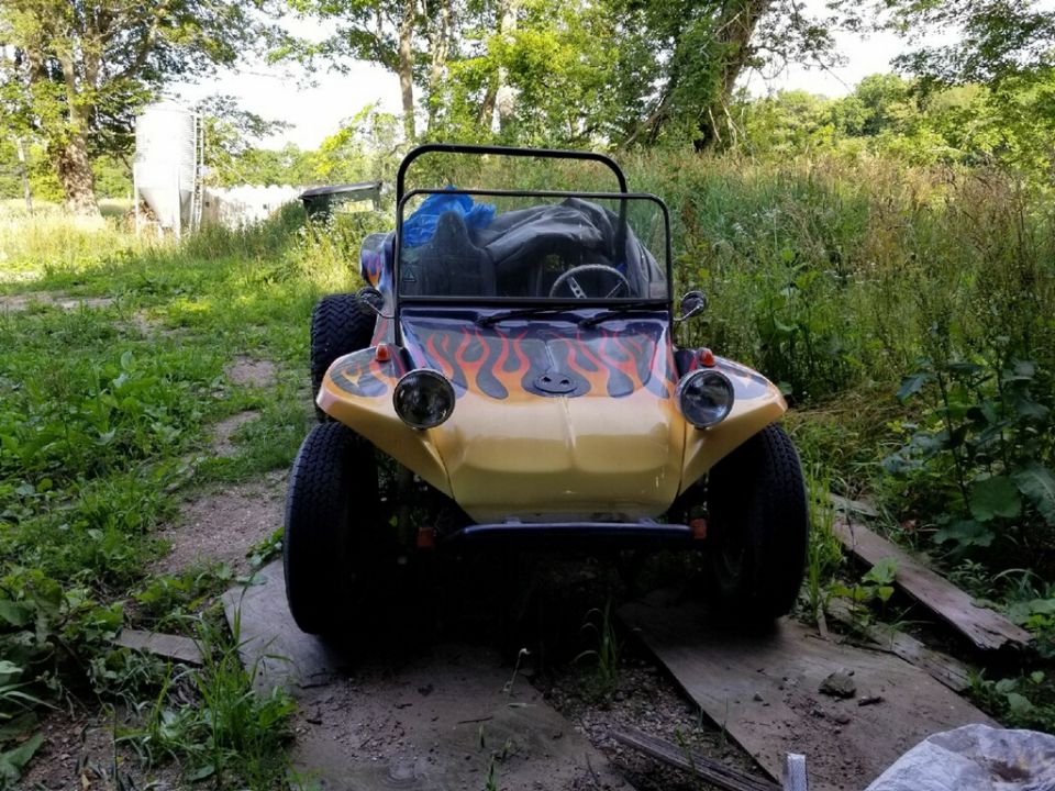 Yellow custom dune buggy with flame decals on the hood, parked outdoors