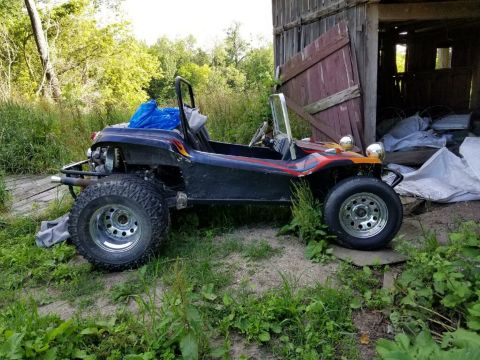 1968 Ford Mustang - This dune buggy sits parked outdoors next to an old wooden barn, with overgrown vegetation surrounding it.