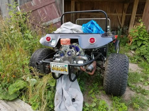1968 Ford Mustang - A custom dune buggy sits in a grassy area next to a wooden structure, its engine exposed.