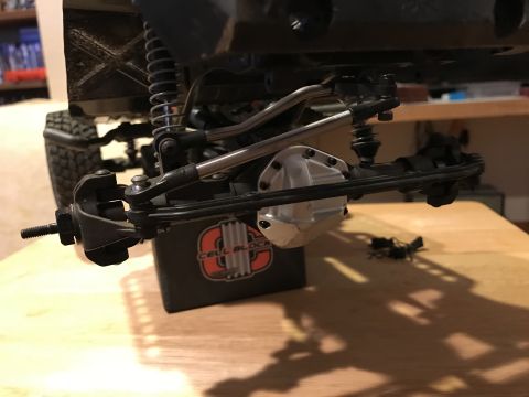 1989 Ford Bronco - Close-up view of the front suspension and differential of an RC car, with the 'CELL BLOCK' logo visible on a support.