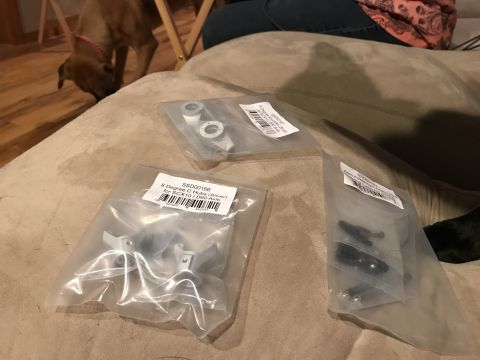 1989 Ford Bronco - Bagged RC car hop-up parts are laid out on a couch, with a dog visible in the background.