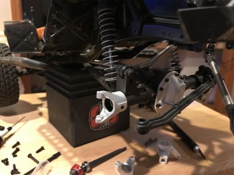 1989 Ford Bronco - Various metal and plastic parts for a remote control car's suspension system are laid out with tools.