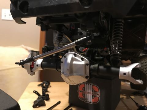 1989 Ford Bronco - Detailed view of the suspension and drivetrain parts of a remote control vehicle, with 'CELL BLOCK' visible on a stand.