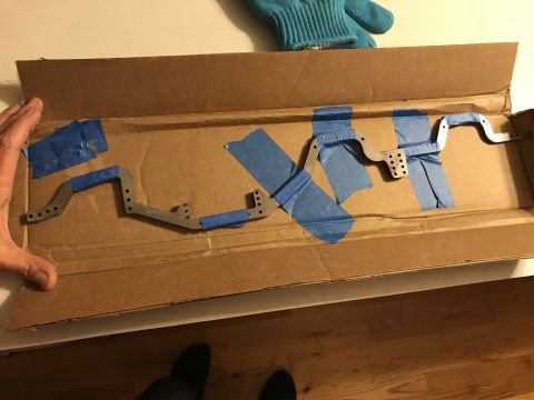 1989 Ford Bronco - RC car chassis parts are taped inside a cardboard box, ready for assembly.