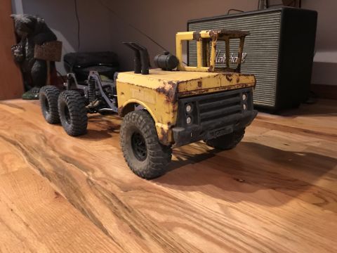 1989 Ford Bronco - This toy truck has a weathered yellow body, dual rear wheels, and aggressive off-road tires.