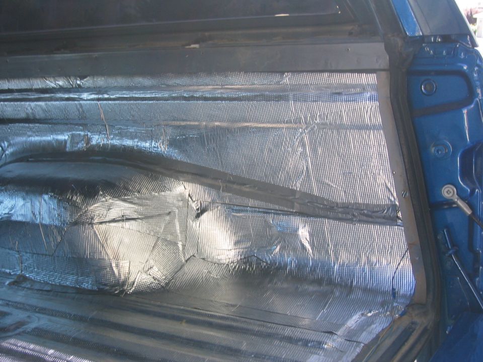 Foil-faced sound-deadening insulation applied inside a blue vehicle body panel