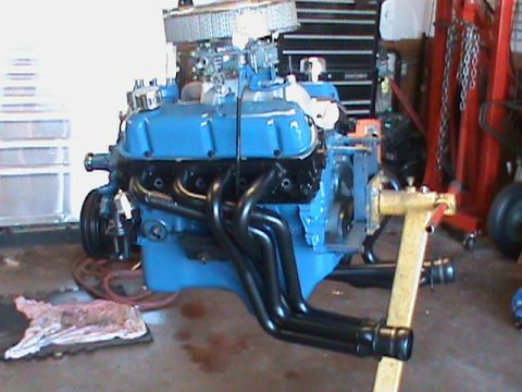 1986 Ford Bronco - A blue engine with black headers is mounted on a yellow engine stand in a garage setting.