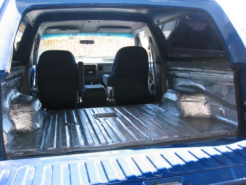 1989 Ford Bronco - The rear cargo area of a blue SUV has been lined with sound deadening material.