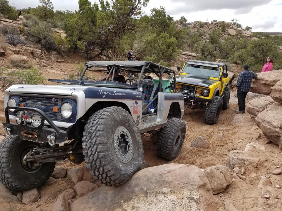 Two modified Ford Broncos on a rocky off-road trail.