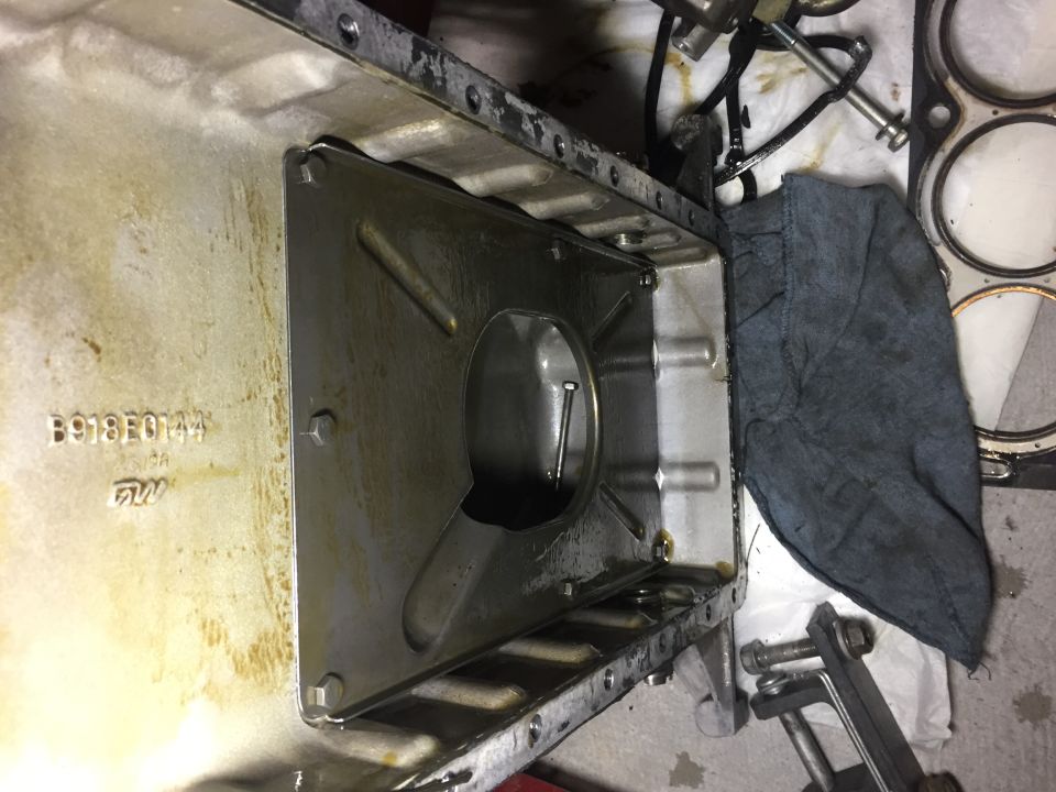 Engine oil pan interior with baffle plate and text B918E0144 FW