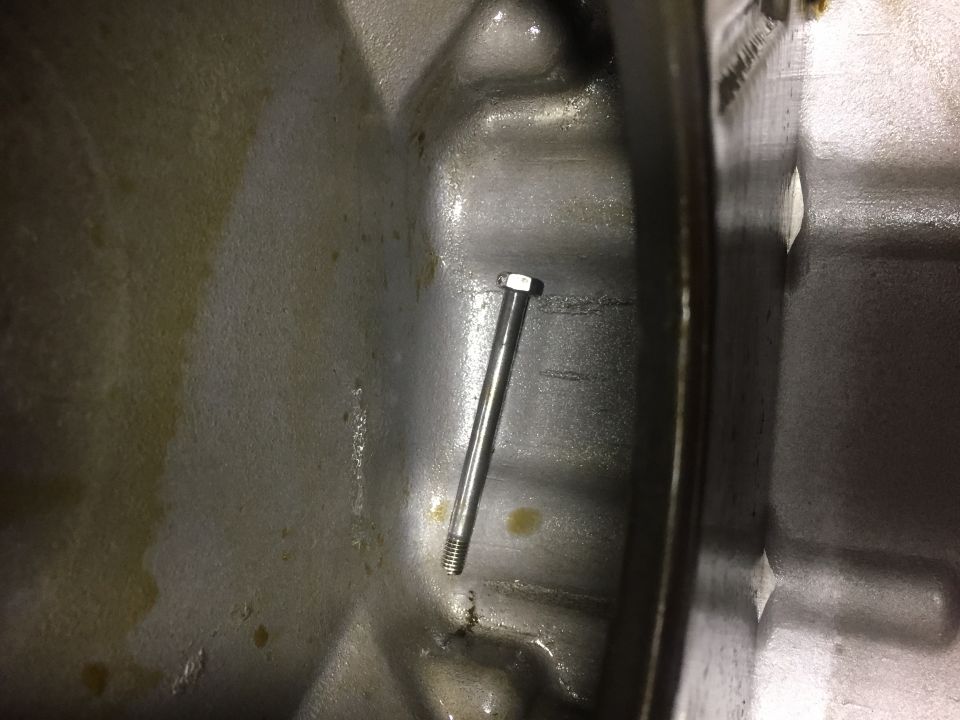 Close-up of a bolt inside a greasy engine component.
