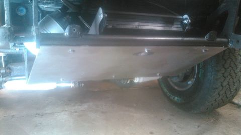 1992 Ford Bronco - A silver skid plate is mounted to the undercarriage of a vehicle, extending forward from the front tire. The skid plate is secured by bolts…