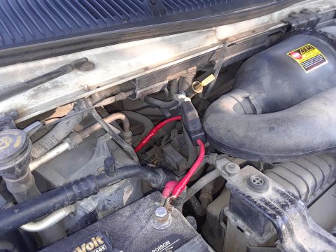 1999 Ford E250 - Close-up view of the engine bay, focusing on the battery and associated wiring.