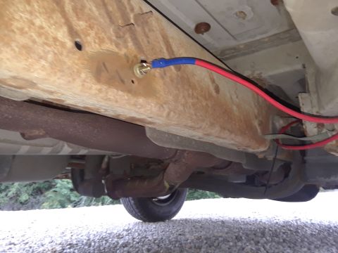 1999 Ford E250 - The underside of a vehicle shows extensive rust on the frame and exhaust components, with visible wiring.