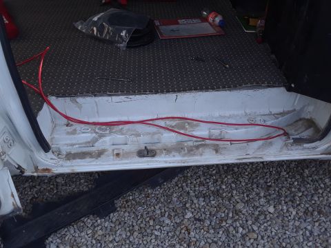 1999 Ford E250 - The interior cargo area of a 1999 Ford E250 shows red wiring running along the floor near the door sill.
