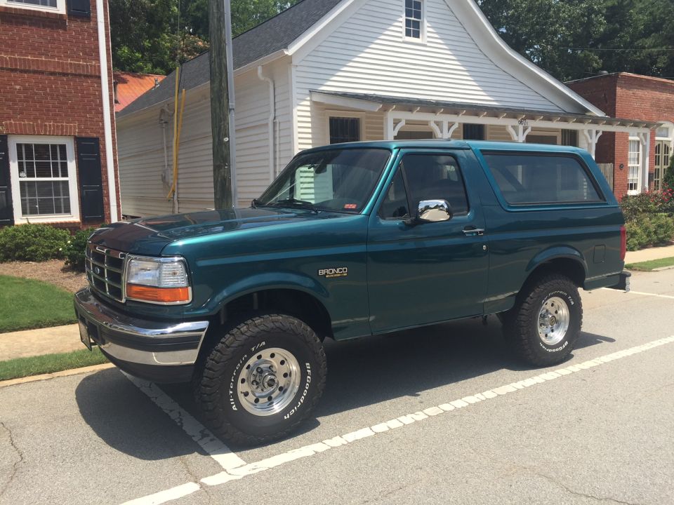 Green 1996 Ford Bronco parked on street, side view