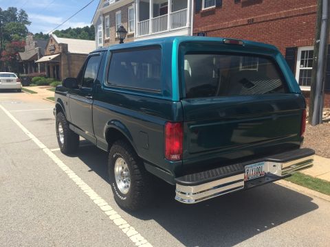 1996 Ford Bronco - Rear view of a dark green 1996 Ford Bronco parked on a street.