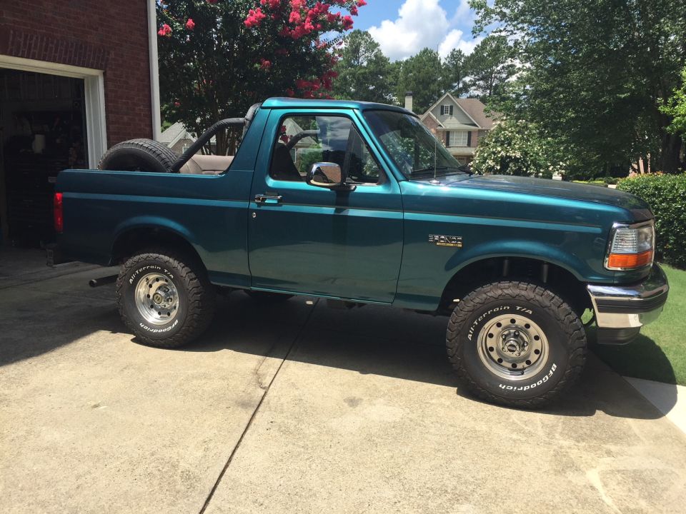 Teal 1996 Ford Bronco with spare tire on back, parked on driveway