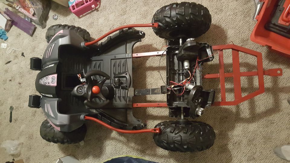 Underside view of a toy ATV chassis with exposed wiring and motors